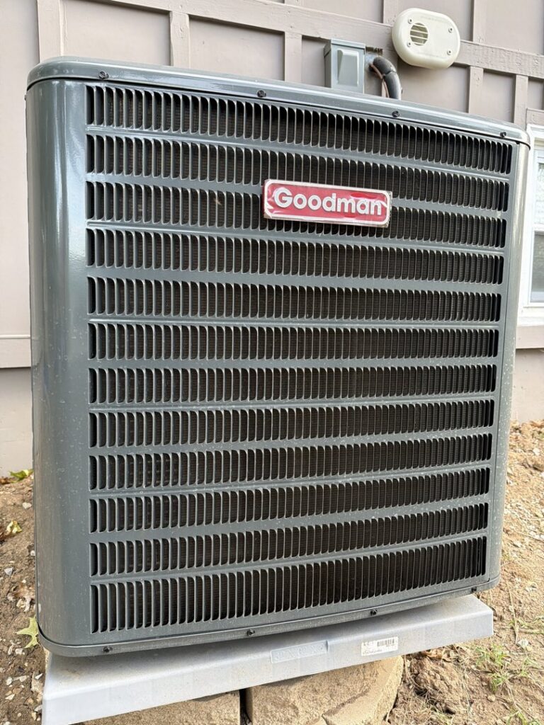 A newly installed Goodman outdoor air conditioning unit next to a residential building by Dad's Heating and Cooling in Blue Springs, MO.