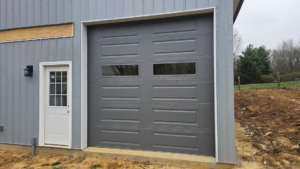 A newly installed gray garage door with windows on a building exterior by A+ Garage Door Repair in Evansville, IN.