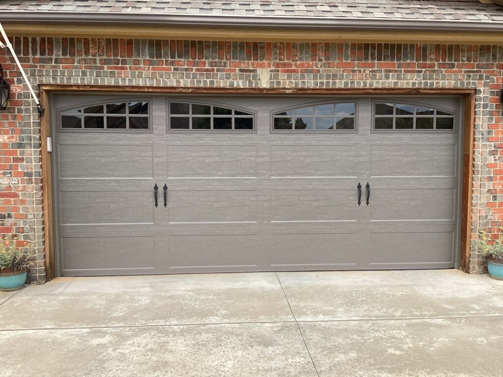 A newly installed grey residential garage door with arched windows by CCM Overhead Doors in Oklahoma City, OK.