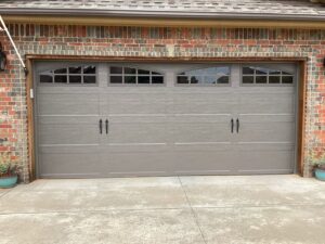 A newly installed grey residential garage door with arched windows by CCM Overhead Doors in Oklahoma City, OK.