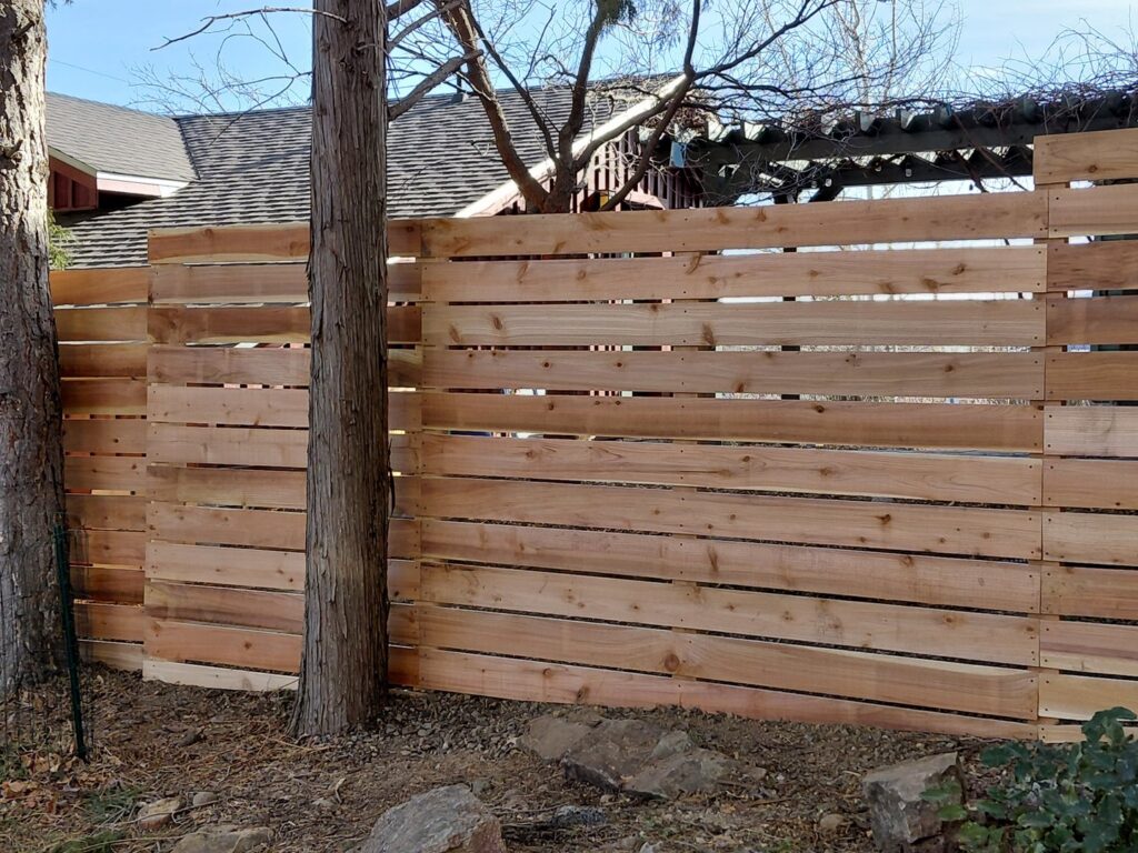 A newly installed horizontal slat wood fence in a residential backyard by Done Wright Fencing and Welding in Denver, CO.