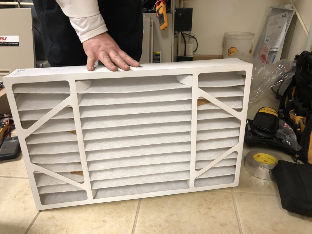 A hand holding a new HVAC air filter, ready for replacement by All Comfort Services in Madison, WI