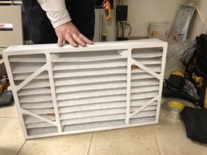 A hand holding a new HVAC air filter, ready for replacement by All Comfort Services in Madison, WI