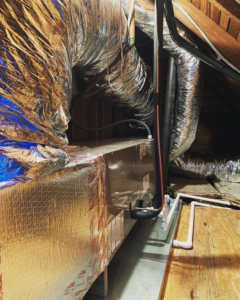 A newly installed or well-maintained HVAC air handler unit with insulated ductwork in an attic by Comfort Pros in Mobile, AL.
