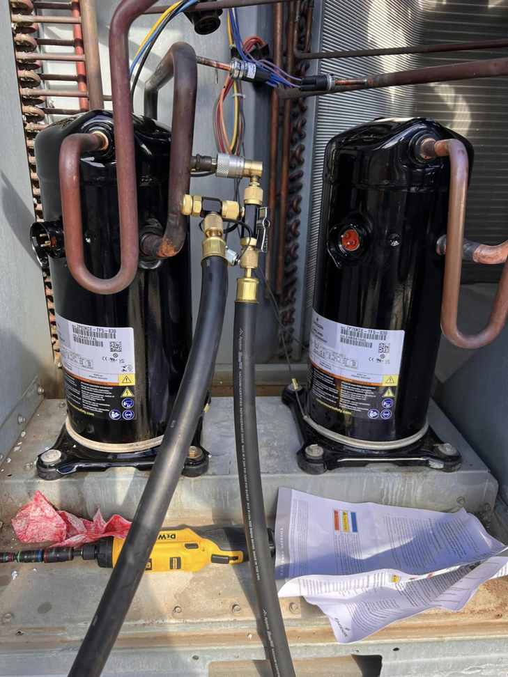 Two new HVAC compressors installed with refrigerant lines and service hoses by Mead Heating and Cooling in Kansas City, MO.
