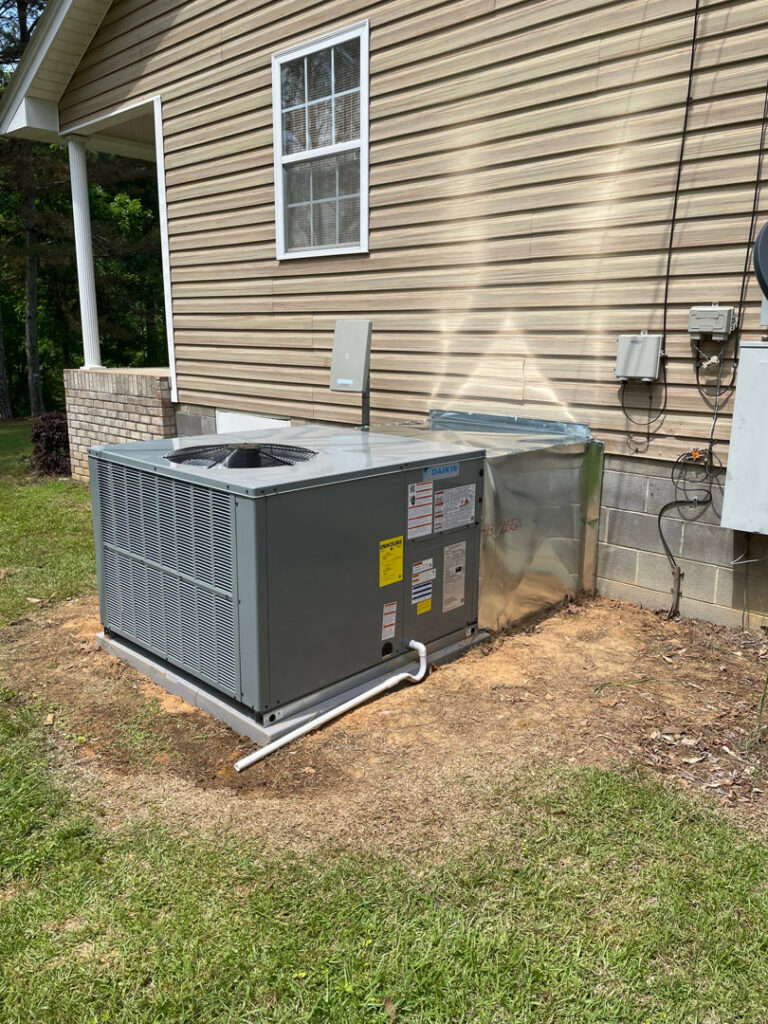 A newly installed outdoor HVAC condenser unit and associated ductwork next to a residential building by Bama Air Systems in Cullman, AL.