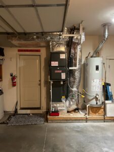 A newly installed Goodman HVAC furnace and water heater system with ductwork in a residential garage by Integrity Heating And Air LLC in Nampa, ID