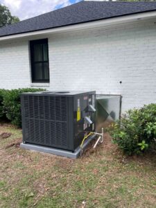 A newly installed outdoor HVAC unit next to a white brick residential building by American Air Solutions in Summerville, SC.