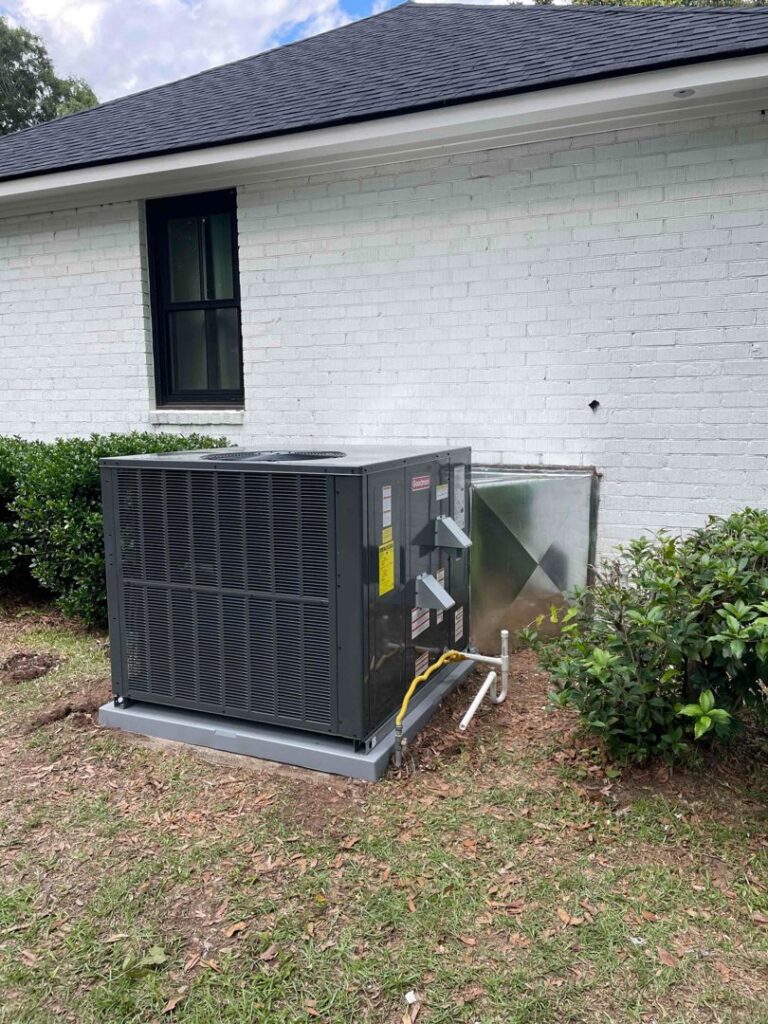 A newly installed outdoor HVAC unit next to a white brick residential building by American Air Solutions in Summerville, SC.