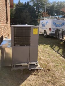 A newly installed outdoor HVAC unit next to a brick building, with a Your Angel Heating And Cooling LLC service van in Cary, NC.