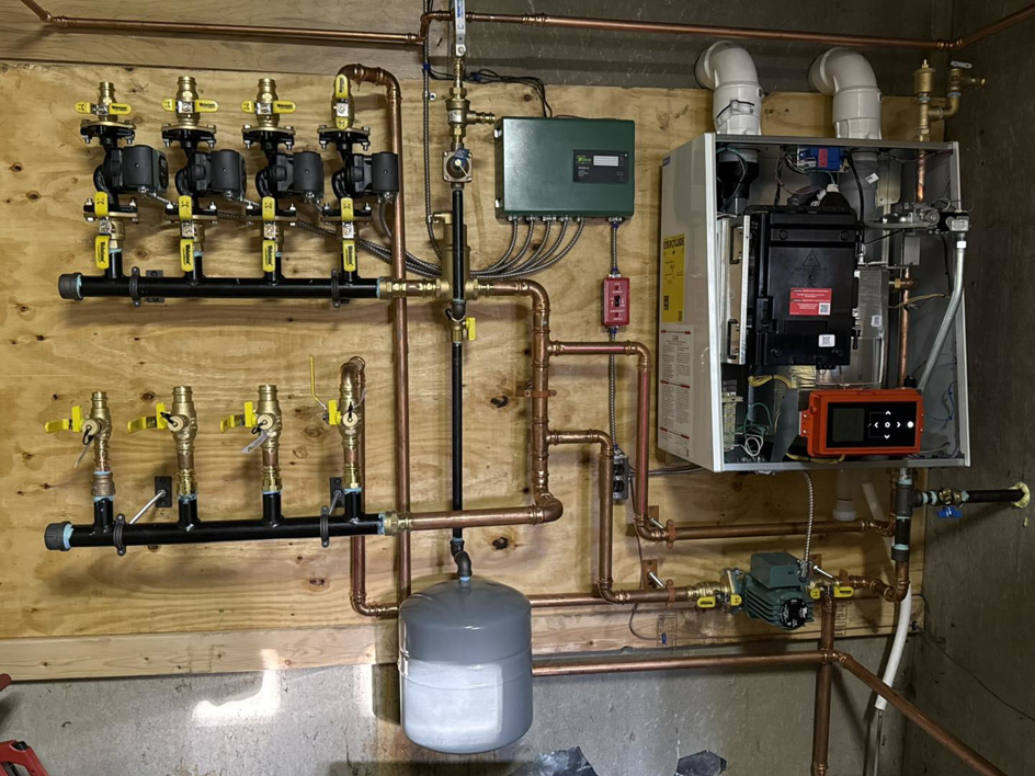 A newly installed hydronic heating system with a boiler and copper piping by Boudreau's Heating in Vassalboro, ME.