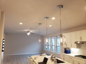 A modern kitchen and living room with newly installed pendant lights, recessed lighting, and a ceiling fan by Davis Electric in Cleveland, OH.