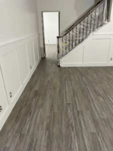 A newly installed laminate or vinyl plank flooring in a room with stairs covered for protection by Sy's Discount Carpets in Los Angeles, CA