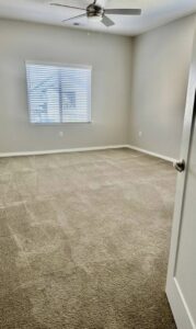 A bedroom with a newly installed light brown carpet by Keystone Carpet & Tile in Omaha, NE.