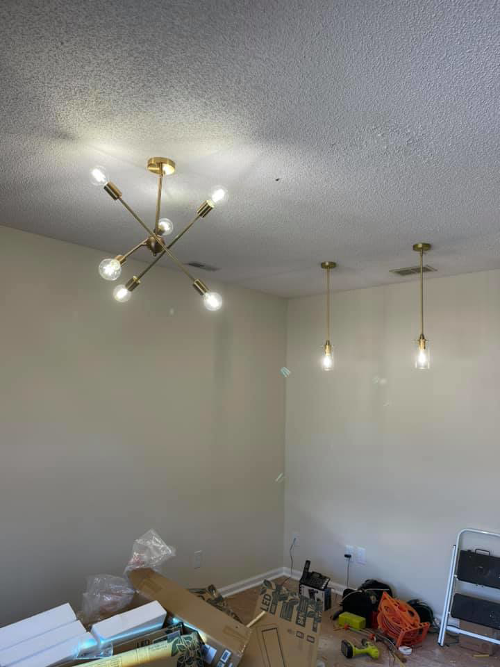 A room with newly installed modern light fixtures, including a chandelier and pendant lights, by CJ Lighting Solution LLC in Greensboro, NC.
