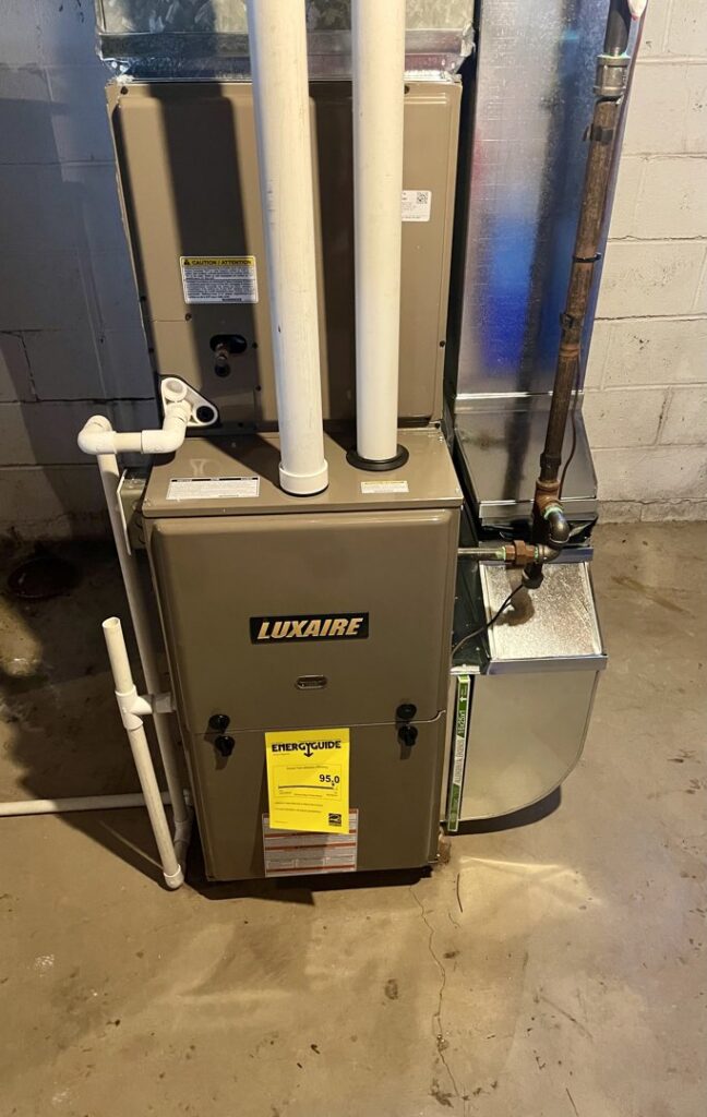 A newly installed Luxaire furnace unit with new ductwork and piping in a basement by Cousins Heating & Cooling in Lansing, MI.