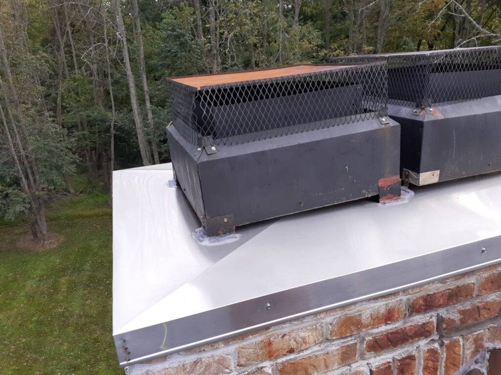 Newly installed large metal chimney caps on a brick chimney, showcasing a professional chimney service by Colombus Chimney in Elizabeth, NJ.