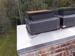 Newly installed large metal chimney caps on a brick chimney, showcasing a professional chimney service by Colombus Chimney in Elizabeth, NJ.