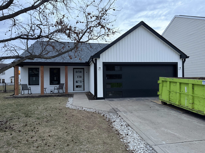 A newly installed modern black garage door on a white house by 365 Construction Group in Indianapolis, IN.
