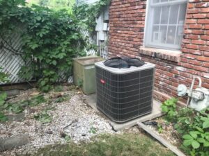 A new Bryant outdoor AC condenser unit installed next to an older unit by DeHart Plumbing, Heating, & Air in Sparks, NV.