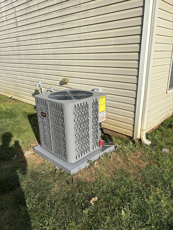 A new outdoor AC condenser unit installed next to a residential building by Dan Deckard Hvac in Charlotte, NC