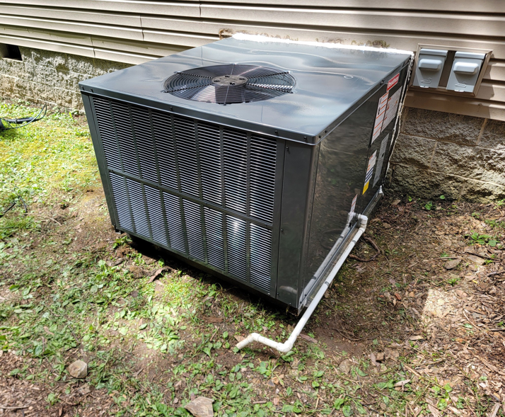 A new outdoor AC condenser unit installed next to a residential building by Smoky Mountain Ducts & Vents in New Market, TN.