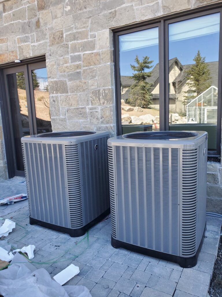 Two new outdoor air conditioning condenser units installed outside a building by Diamond L Plumbing & HVAC in Salt Lake City, UT.