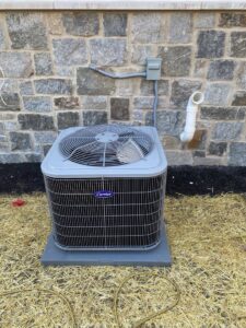 A newly installed outdoor air conditioning condenser unit next to a stone wall by Chad Byers - Edge Guys Heating & Cooling in Carmel, IN.