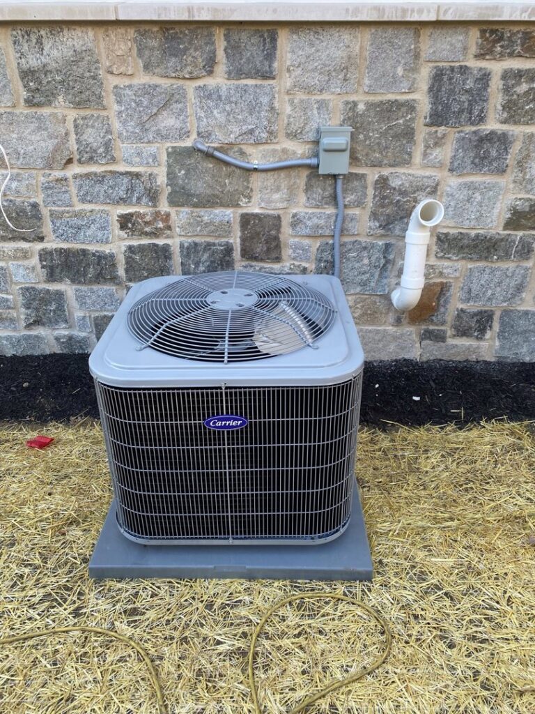 A newly installed outdoor air conditioning condenser unit next to a stone wall by Chad Byers - Edge Guys Heating & Cooling in Carmel, IN.