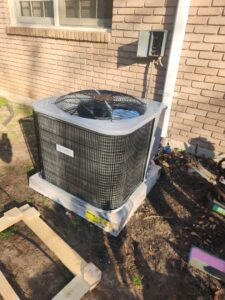 A new outdoor air conditioning unit installed on a concrete pad next to a brick house by Netherland Air Conditioning LLC in Mobile, AL.