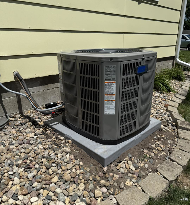 A newly installed outdoor air conditioning unit next to a residential building by Island Heating & Air in Grand Island, NE