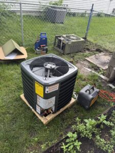 A new outdoor AC unit being installed with an old unit and tools nearby by Trade Allies Heating and Cooling in Ankeny, IA.