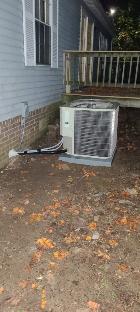A newly installed outdoor HVAC condenser unit next to a residential building by Air Mechanics, LLC in Greensboro, NC.