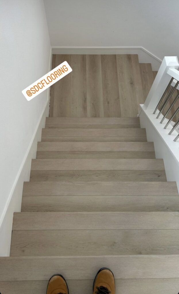 Newly installed light-colored plank flooring on a staircase, showcasing work by Sy's Discount Carpets in Los Angeles, CA