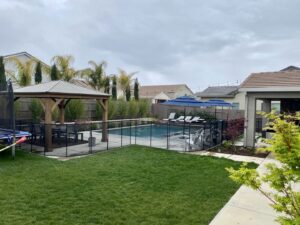A newly installed black mesh pool fence and gate ensuring safety, by Golden State Baby Barrier in Sacramento, CA.