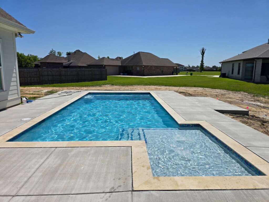 A newly constructed residential swimming pool with an attached spa and clean decking by I10 Pool Plastering LLC in Kenner, LA.