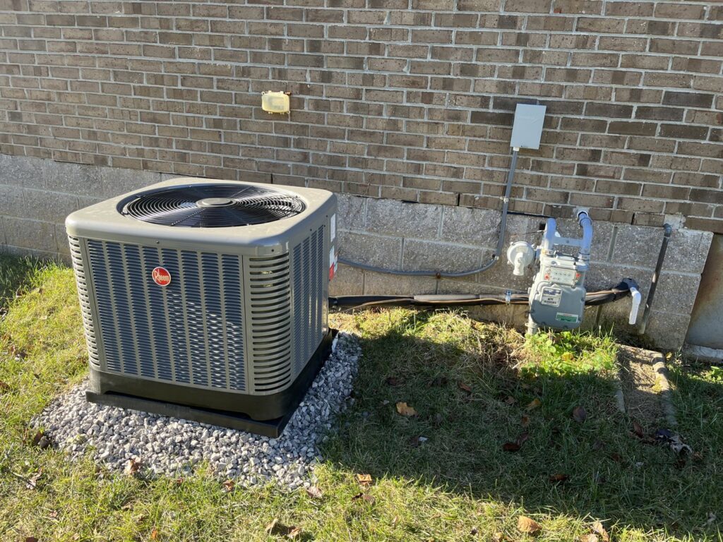 A newly installed Rheem outdoor HVAC condenser unit next to a brick home by GrinHouse HVACR in La Grange, KY.