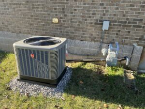 A newly installed Rheem outdoor HVAC condenser unit next to a brick home by GrinHouse HVACR in La Grange, KY.