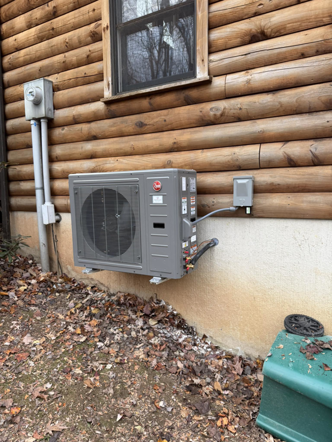 A newly installed Rheem outdoor HVAC unit on a log cabin, expertly placed by Dynamic Comfort Solutions in York, PA.