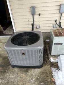A newly installed Ruud outdoor air conditioning unit next to an older unit by Accurate Conditioning in Sayreville, NJ.