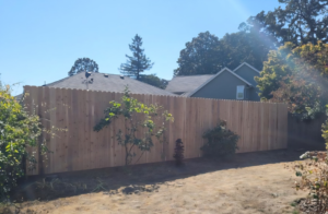 A newly installed scalloped top wood privacy fence in a residential backyard by Howell Fence Inc. in Oregon City, OR.