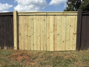 A newly installed single wooden gate or panel, light-colored, integrated into an existing dark fence by Myers & Dunlap Fence Repair in Greenville, SC.