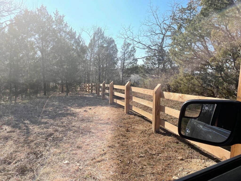A newly installed split-rail wood fence extending into a natural landscape by Exterior Experience LLC in St. Louis, MO.