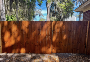 A newly stained wooden privacy fence with a gate installed by Barwick Fence Company in Savannah, GA.