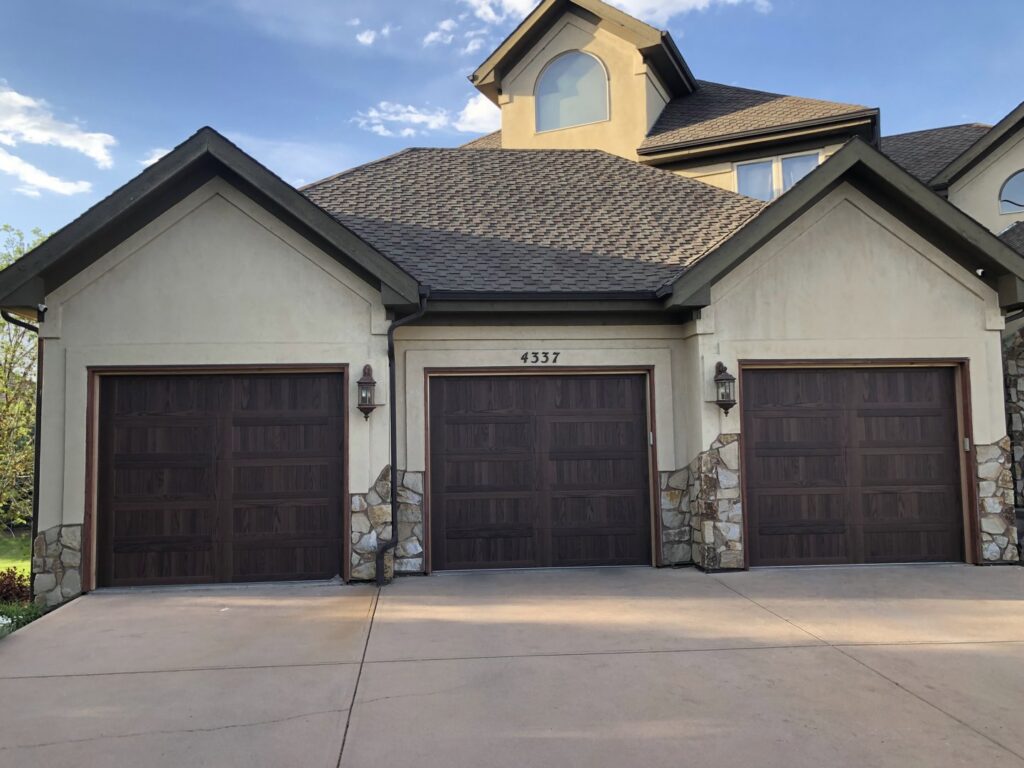 A large house showcasing three newly installed garage doors by Colorado Garage Door Guy in Aurora, CO.