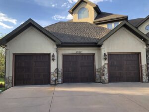 A large house showcasing three newly installed garage doors by Colorado Garage Door Guy in Aurora, CO.