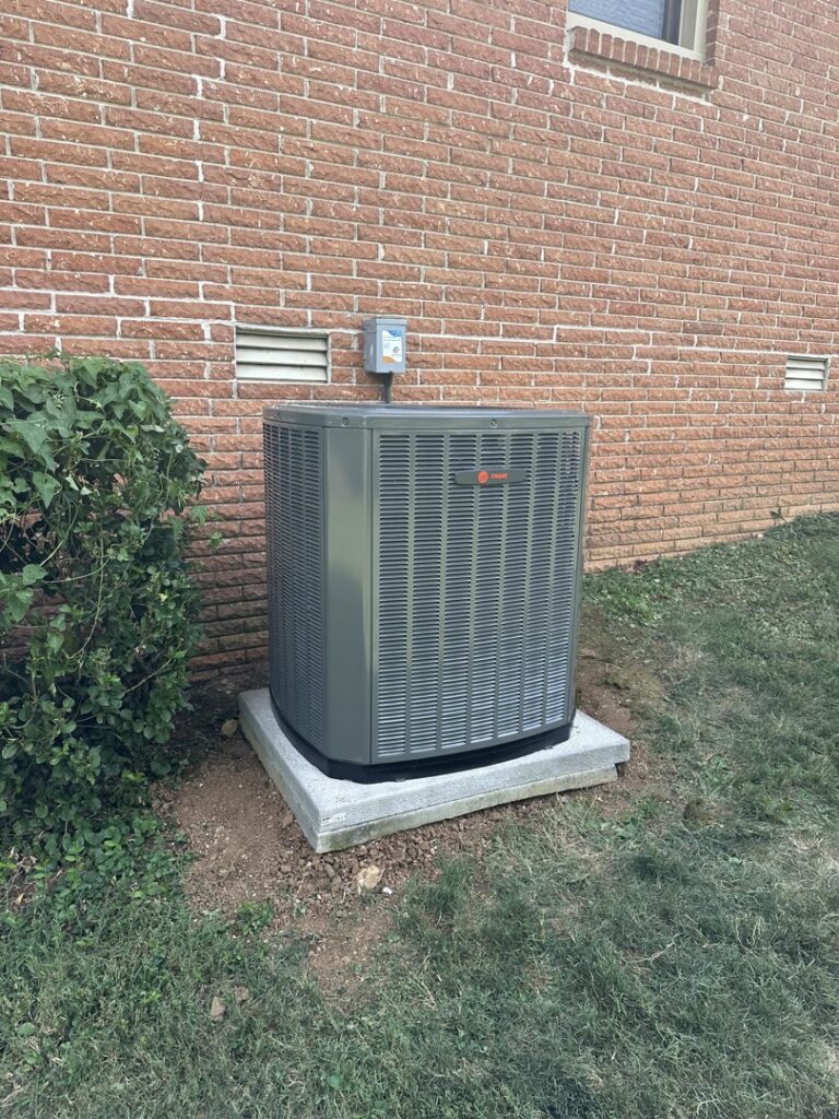 A newly installed Trane outdoor air conditioning unit next to a brick building by Breeze Heating & Cooling Nashville in Nolensville, TN.