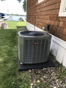 A newly installed Trane air conditioning unit next to a lakeside home by Comfort Solutions Heating and Air Conditioning in Omaha, NE.