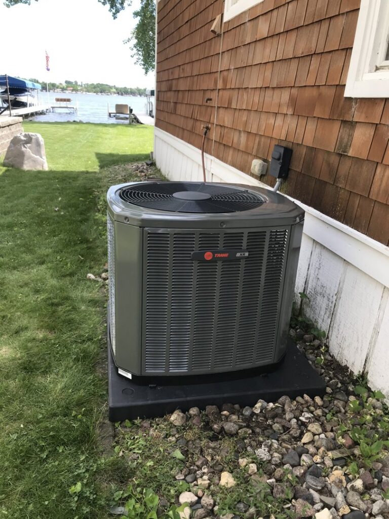 A newly installed Trane air conditioning unit next to a lakeside home by Comfort Solutions Heating and Air Conditioning in Omaha, NE.