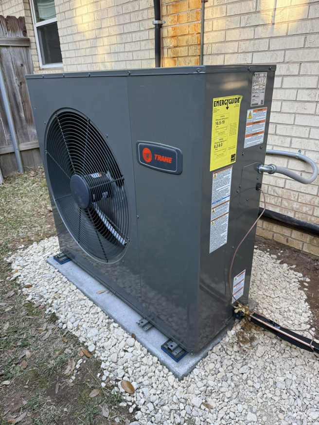 A newly installed Trane outdoor HVAC unit on a gravel bed by Ice Cold A/C & Heating in Bossier City, LA.